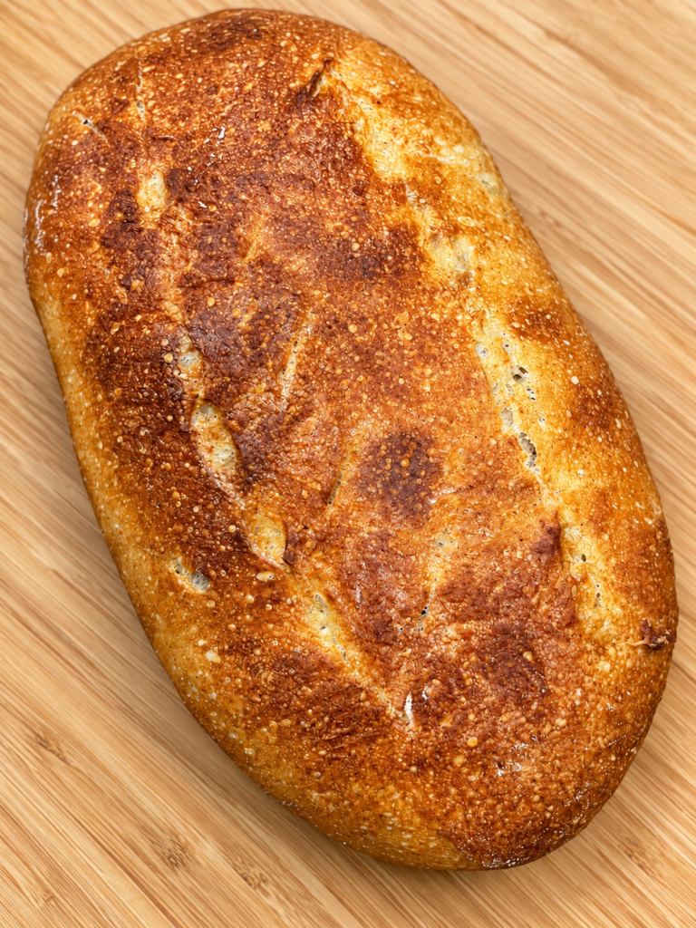Homemade golden-brown sourdough loaf baked without a Dutch oven.